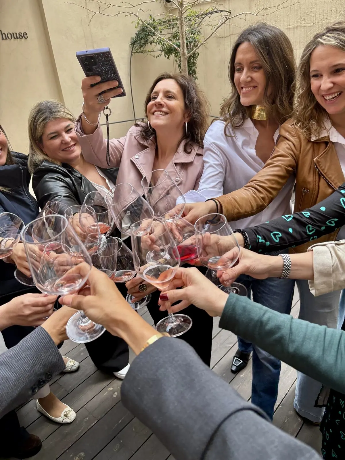 Un grupo de mujeres brinda con copas de vino en una terraza durante un encuentro IKONIKAS